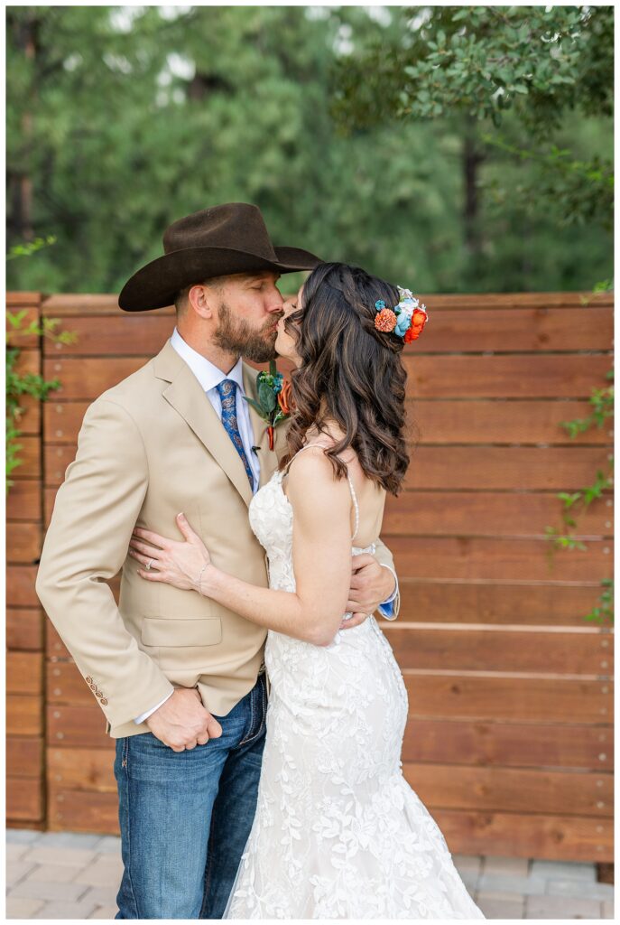 Bride and groom kissing in front of wooden gate at Cabins on Strawberry Hill