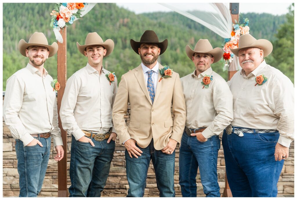 Groomsmen in tan, blue jeans, and cowboy hats. 