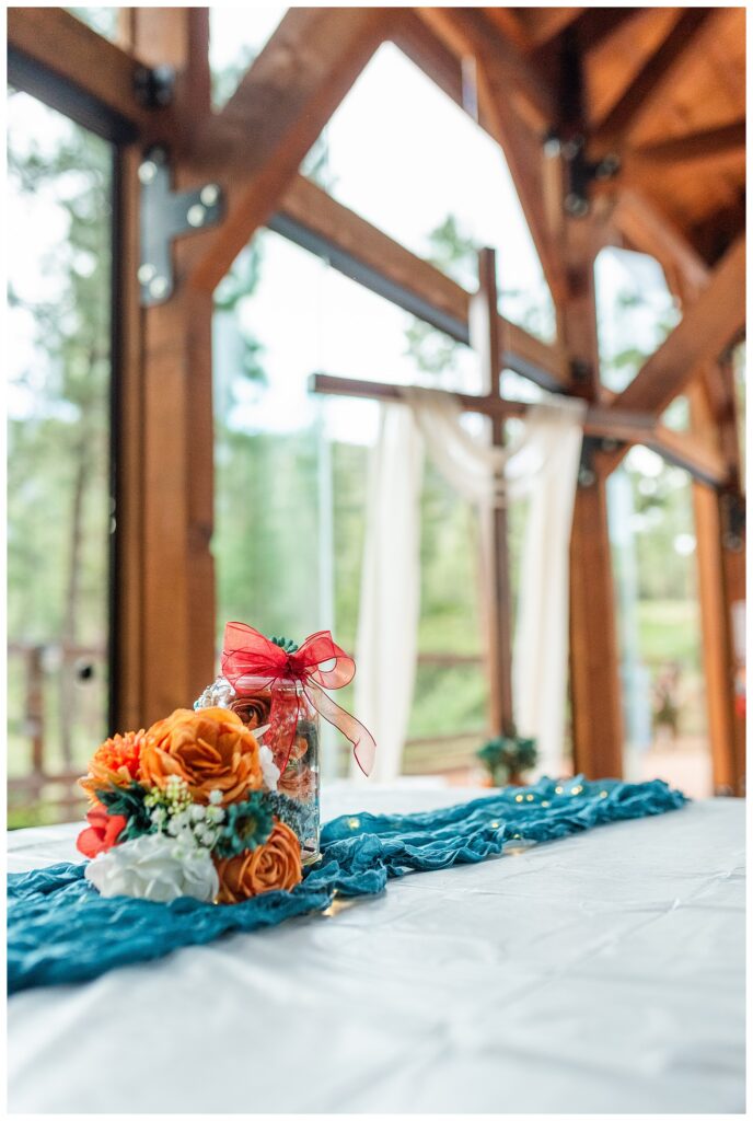 Great Grandma's jar with flowers and cross in background at wedding reception. 