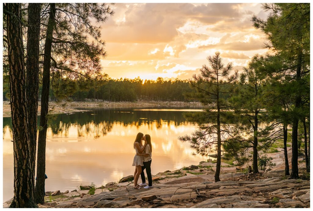 Couple standing on banks of Willow Springs Lake with sunset behind